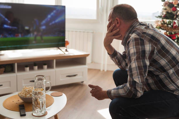 Nervous man watching European football on TV at home